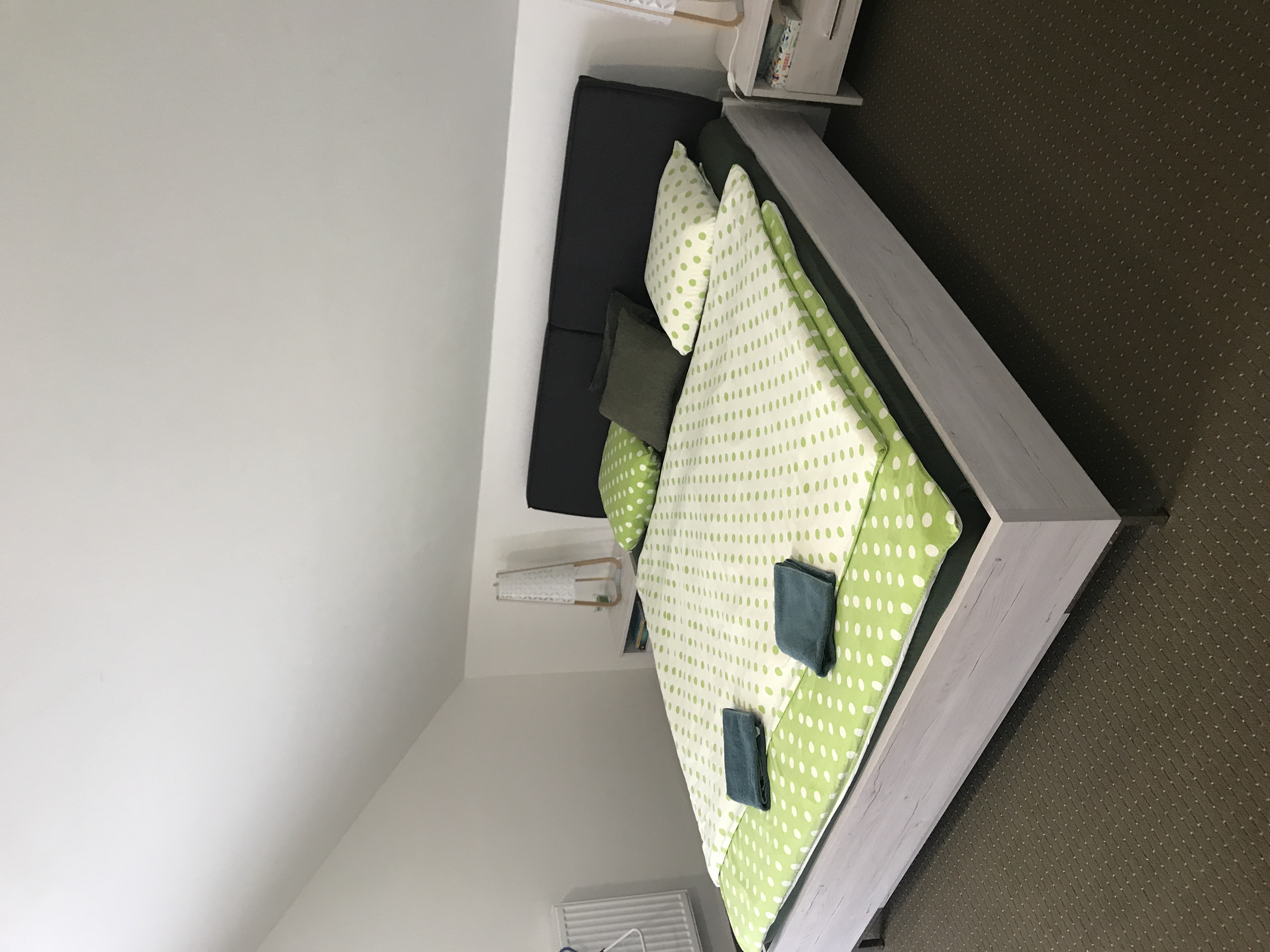 Ložnice s manželskou postelí a nočními stolky v zeleném pokoji.